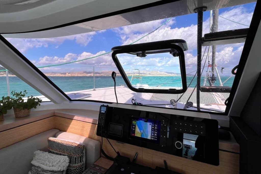 Navigation station inside a catamaran with a view of the water