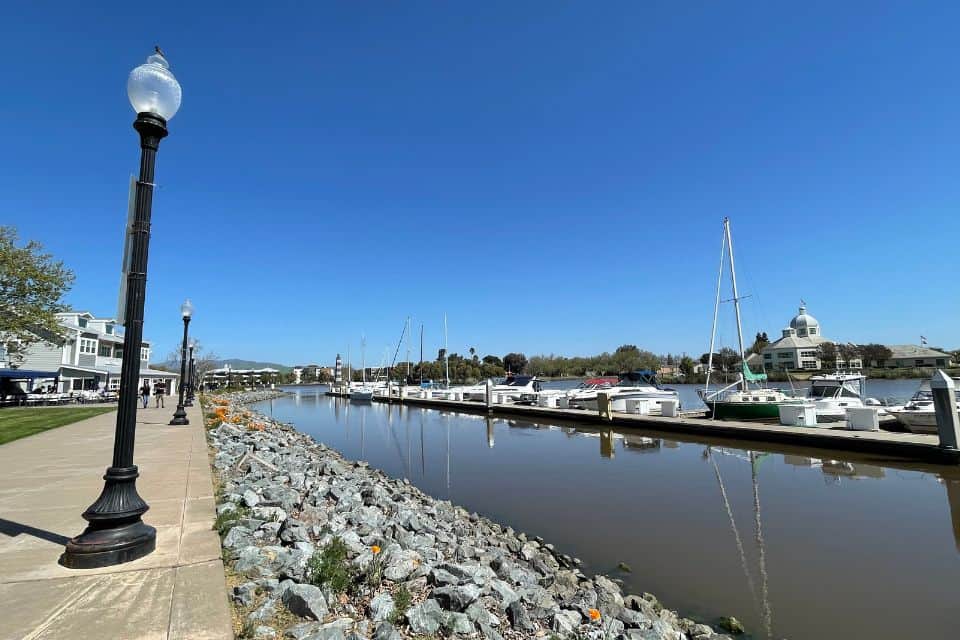 Waterfront walkway beside the Suisun City marina with boats, lamp posts, and buildings along the dock