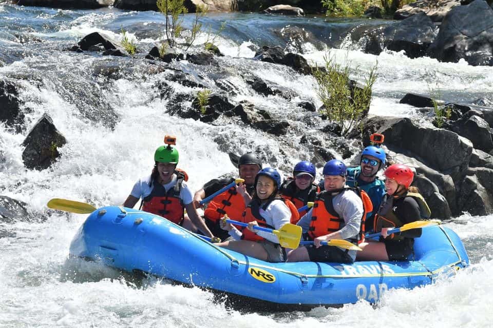 Group of rafters wearing helmets and life jackets on a whitewater rafting trip