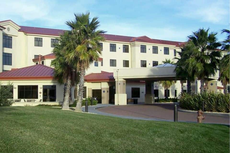 Exterior of the Westwind Inn at Travis AFB with palm trees and a covered entrance