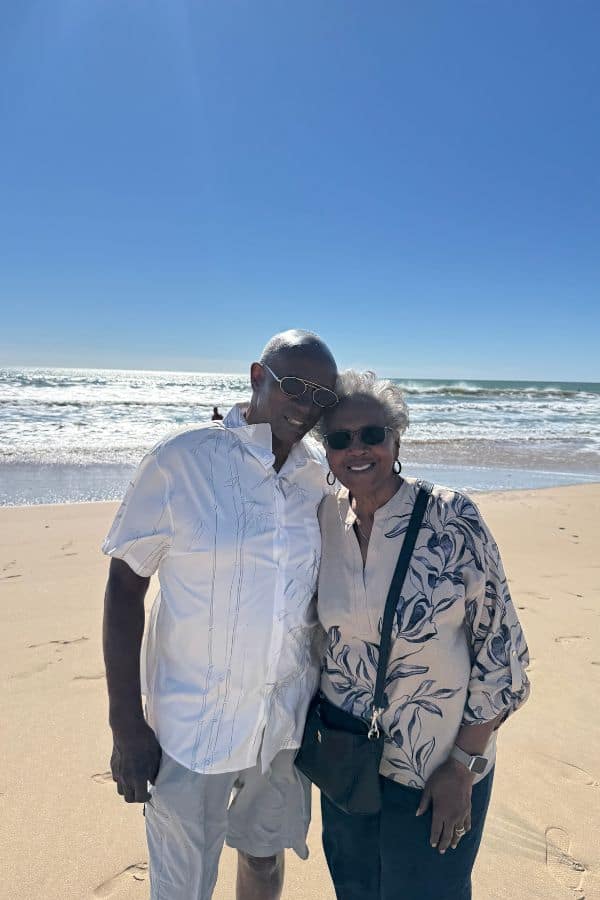 a couple standing on the beach wearing sunglasses