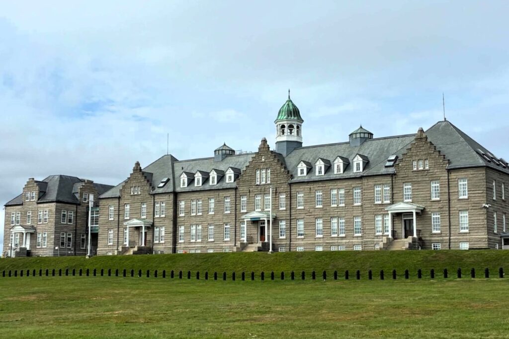 Large stone Naval War College building with a green cupola overlooking a grassy lawn