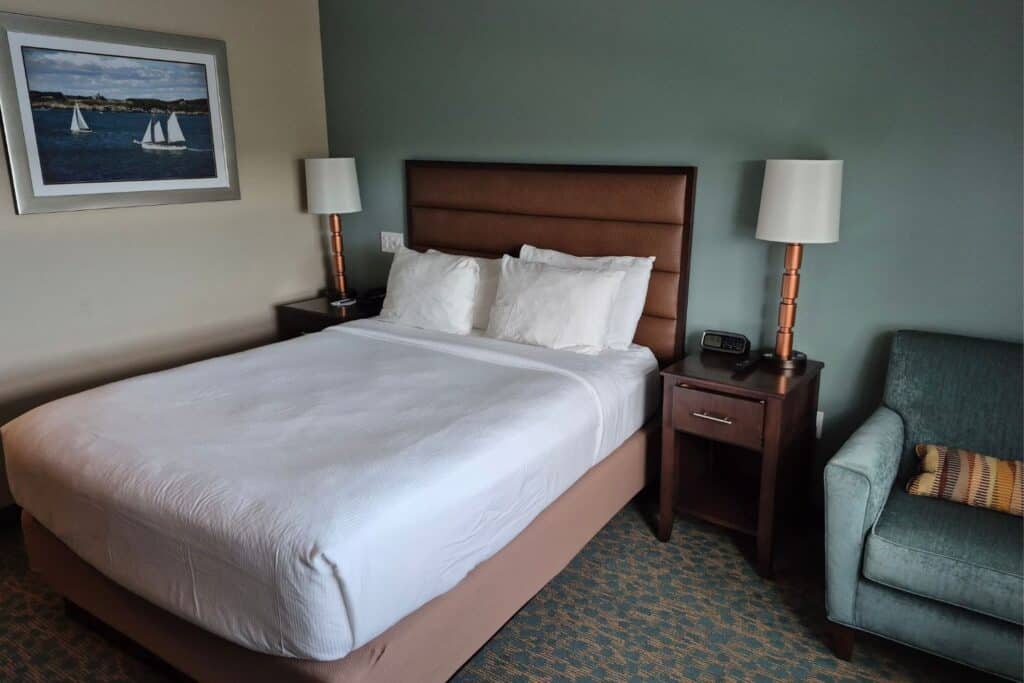 Navy Inn guest room with a queen bed, nightstands, lamps, and armchair