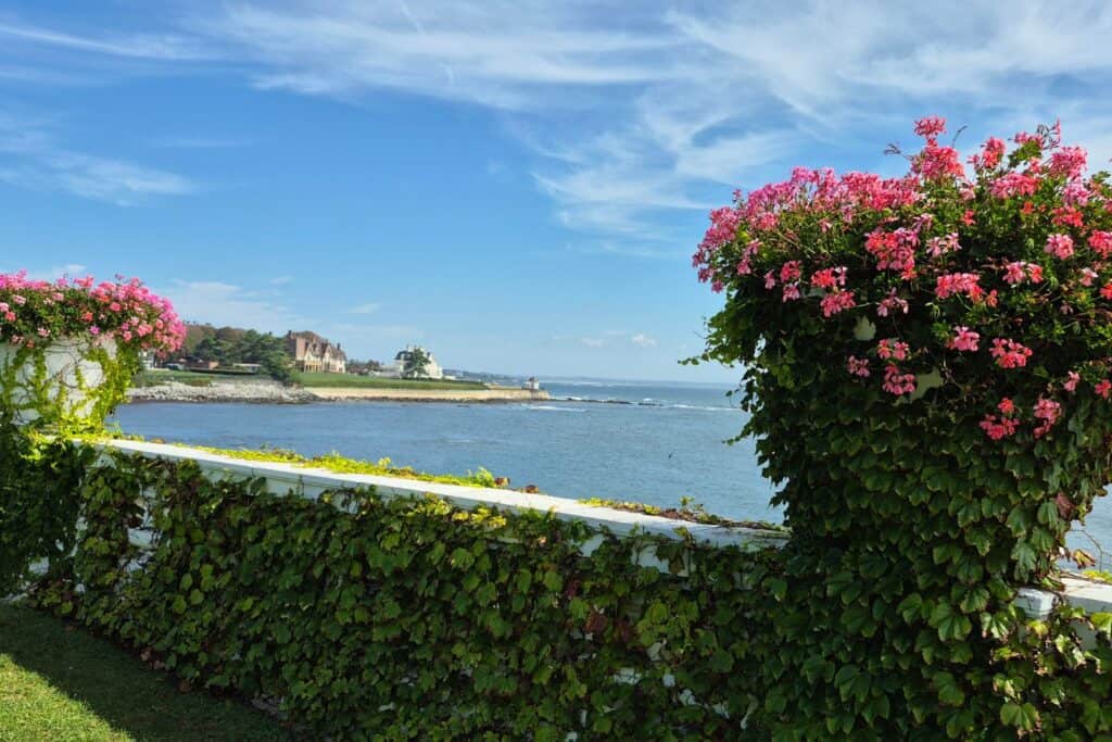 Ocean view framed by pink flowers and ivy-covered walls near Newport’s Cliff Walk