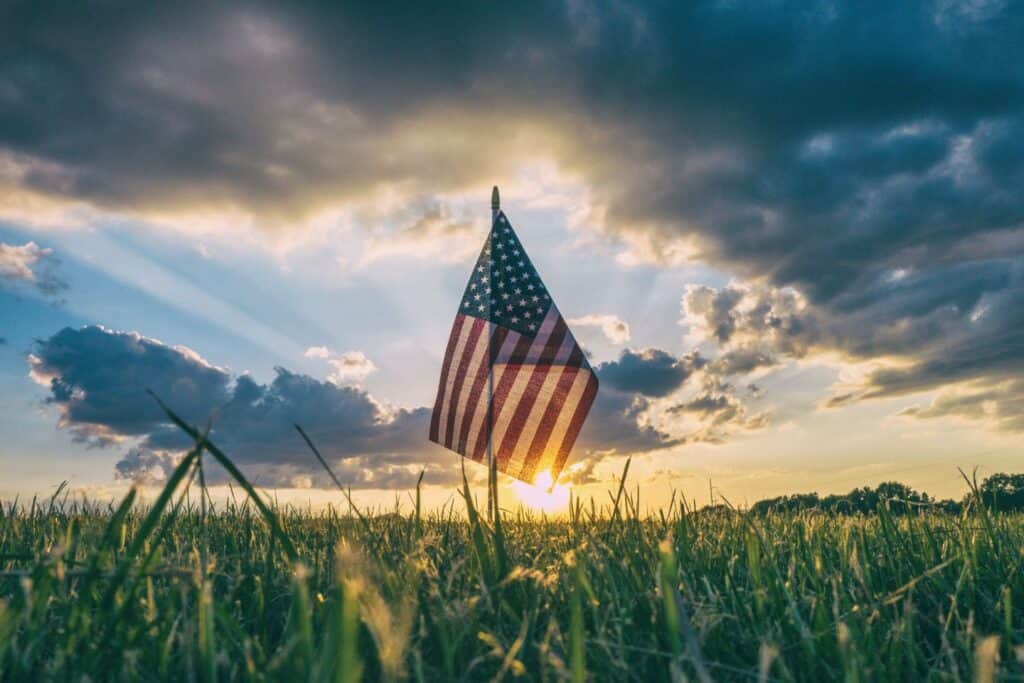 An American flag with the sun setting in the background