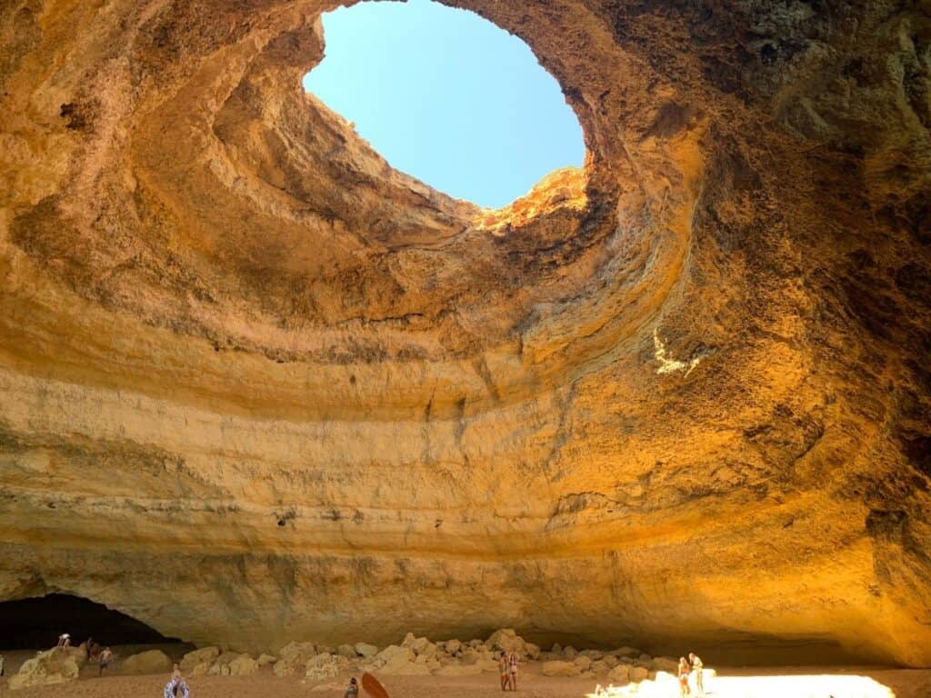A cave with a view of the sky from a hole at the top