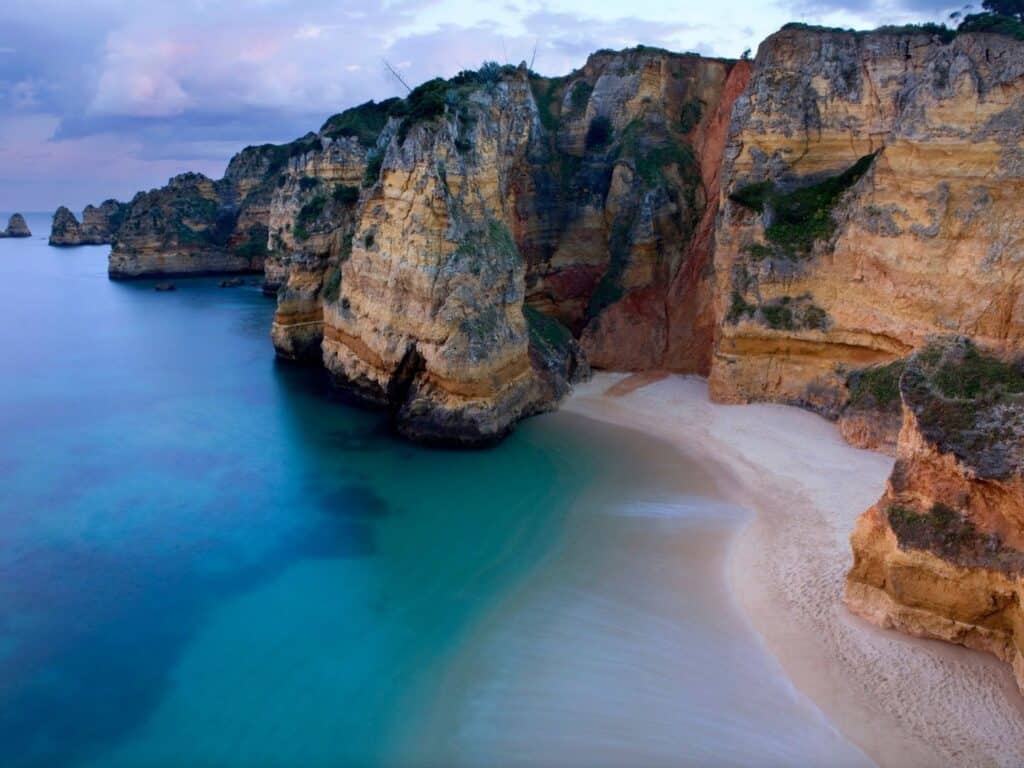 Towering cliff above a beach with turquoise water