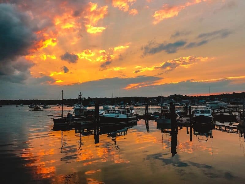 Ships in a harbor with a colorful sunset in the background