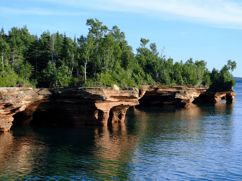 Green trees on sandstone cliffs dropping into a lake