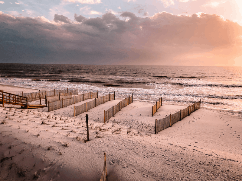 A white sandy beach with clouds on the horizon