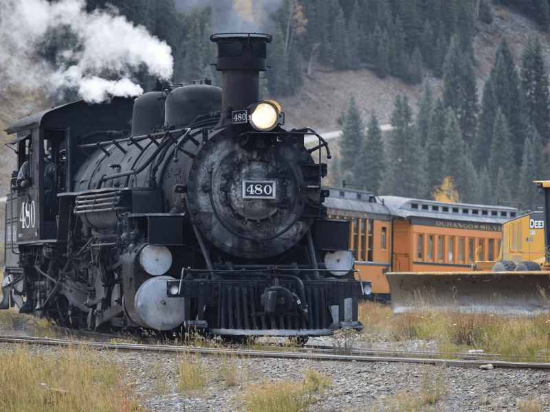 An old steam engine train with orange cars