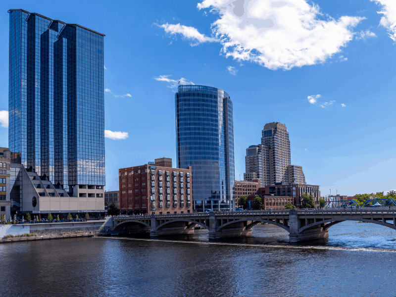 Tall, glass buildings next to a river with a bridge in Grand Rapids