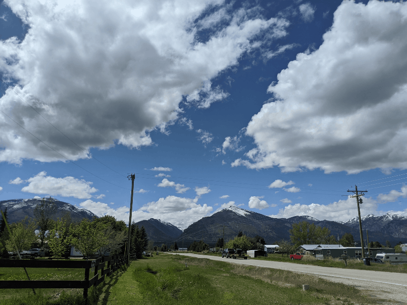 Big blue sky with puffy clouds over a small town surrounded by mountains