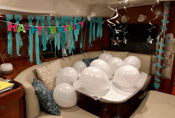 The salon of the boat filled with white balloons and birthday decorations.