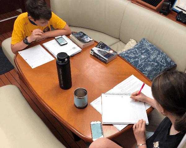 The kids sitting at the kitchen table, doing school work.