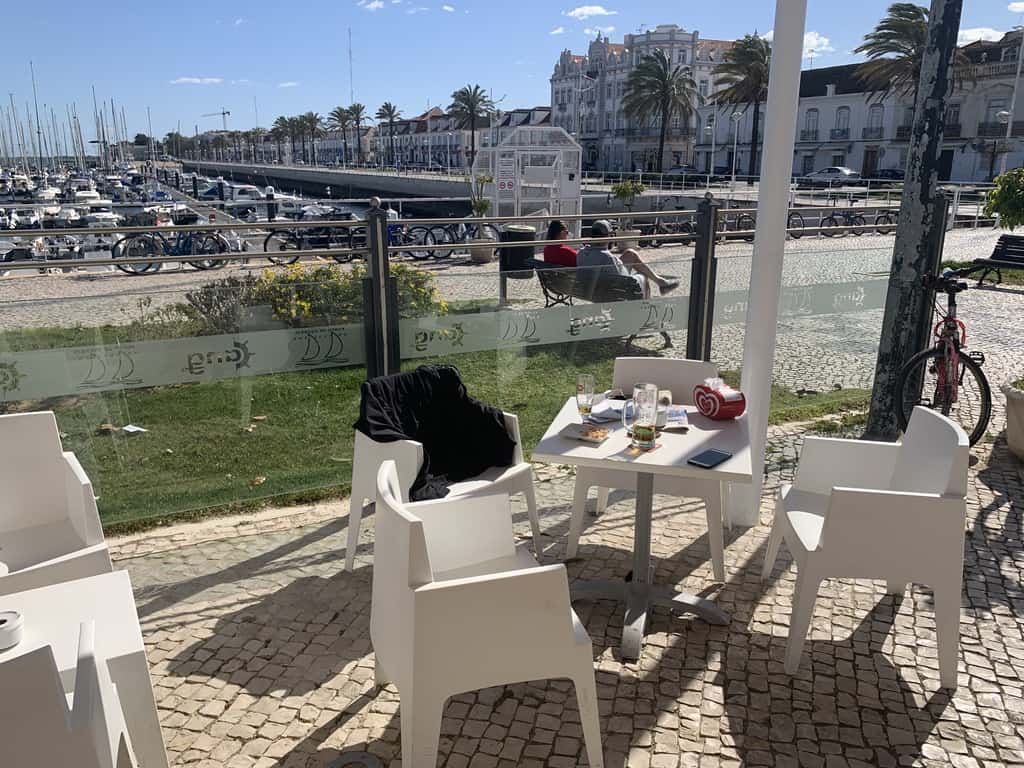 White table and chairs at an outdoor cafe overlooking a marina in Algarve