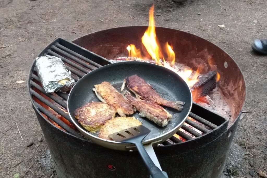 A pan of fish cooking on a grill