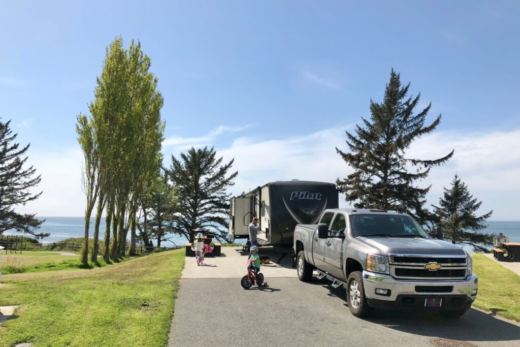 A truck in front of an RV with kids riding bicycles nearby