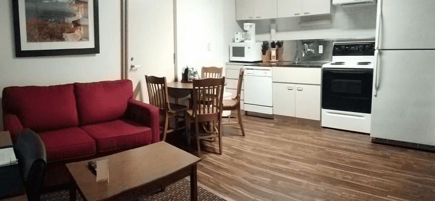 A military hotel room with a red couch and kitchen with dining table