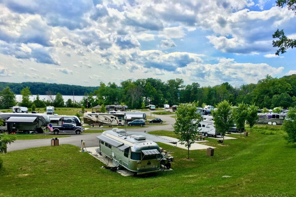 RVs parked on a grassy area by a river