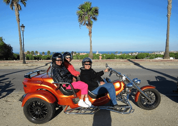 Picture of the author and friends on an orange 3-wheeled motorcycle