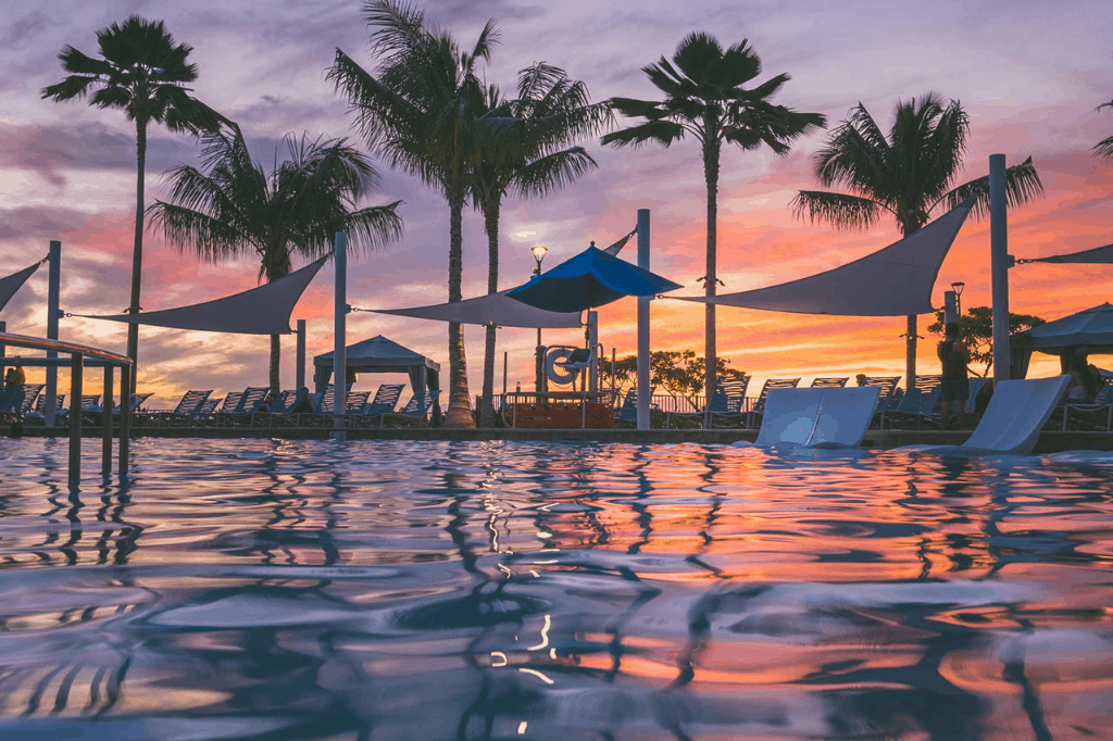 A pool surrounded by deck chairs at dusk