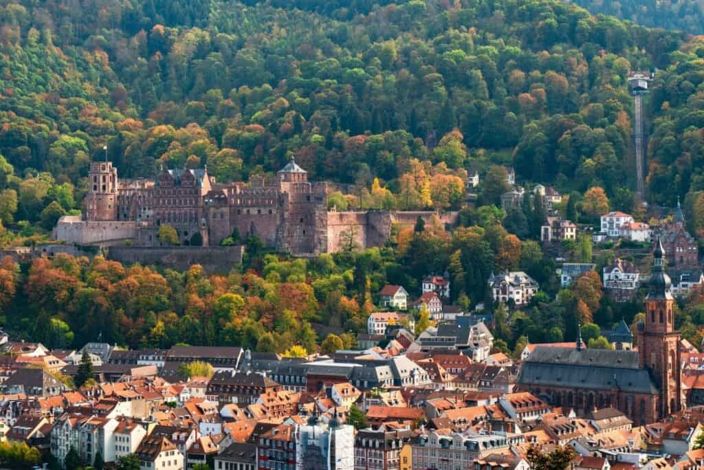 Birds eye view of a German town with a large castle surrounded by green mountains