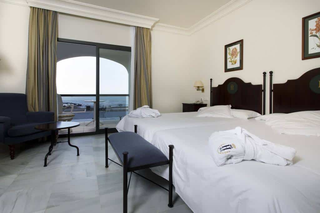 A guest room at Hotel Duque de Najera with two beds and a large window leading out to a balcony