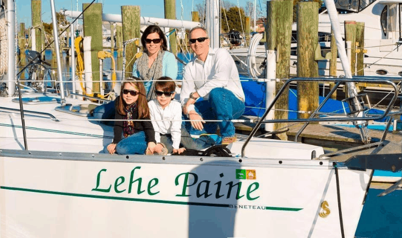 A family of 4 with two young children on the deck of their sailboat, the Lehe Paine.