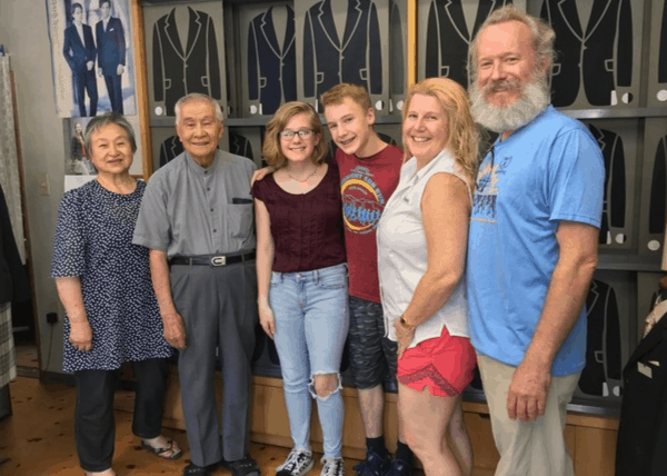 The Reamer family standing next to a Japanese couple in the couple's tailor shop 
