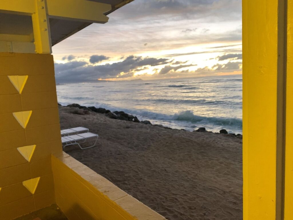 View of the ocean from the yellow wooden porch of a beachfront cottage