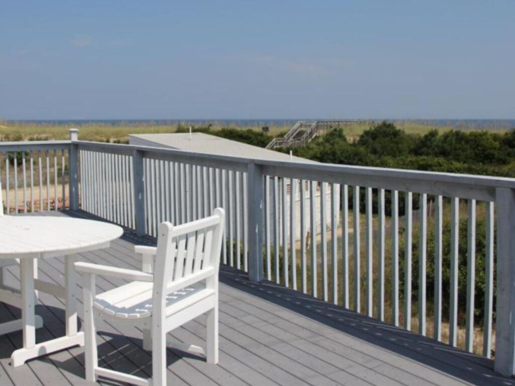 Furniture on a wooden deck with ocean views in the distance