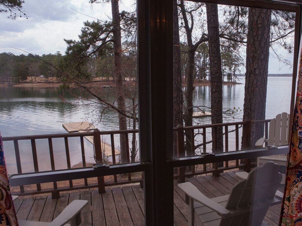A wooden deck with furniture overlooking a lake