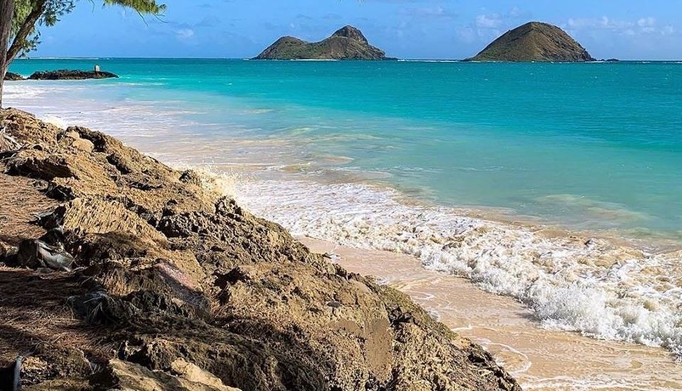 View from a beach with turquoise water and two small islands in the background