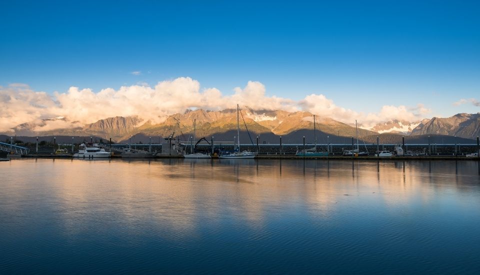 Boats in a harbor with snow-capped mountains in the background