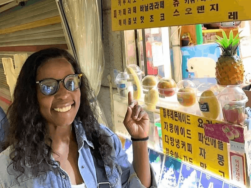 A woman smiling and pointing to menu written in Korean