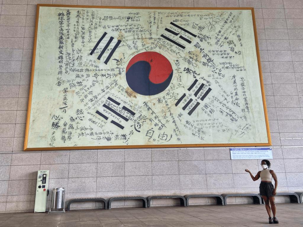 A woman standing in front a giant framed Korean flag