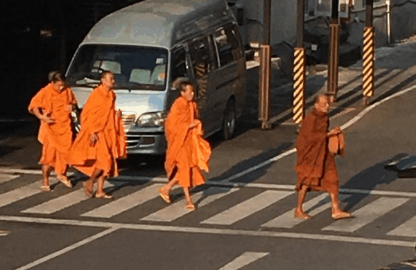 Four monks crossing a busy street