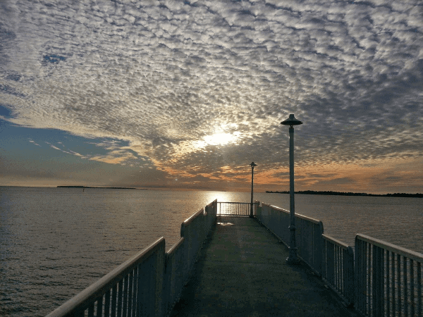 Sunset at the end of a pier surrounded by a small fence