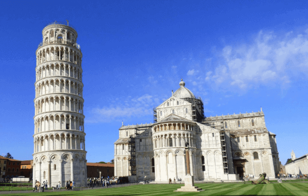 The Learning Tower of Pisa next to the cathedral with a bright blue sky in the background