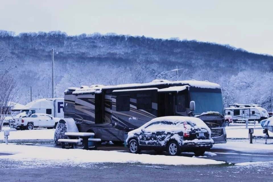 A large motorhome covered with a dusting of snow in an RV park