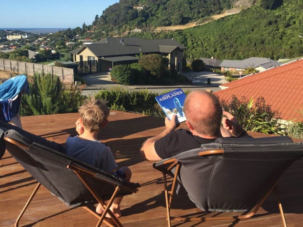A man and his son sitting on a deck, with views of the ocean in the distance