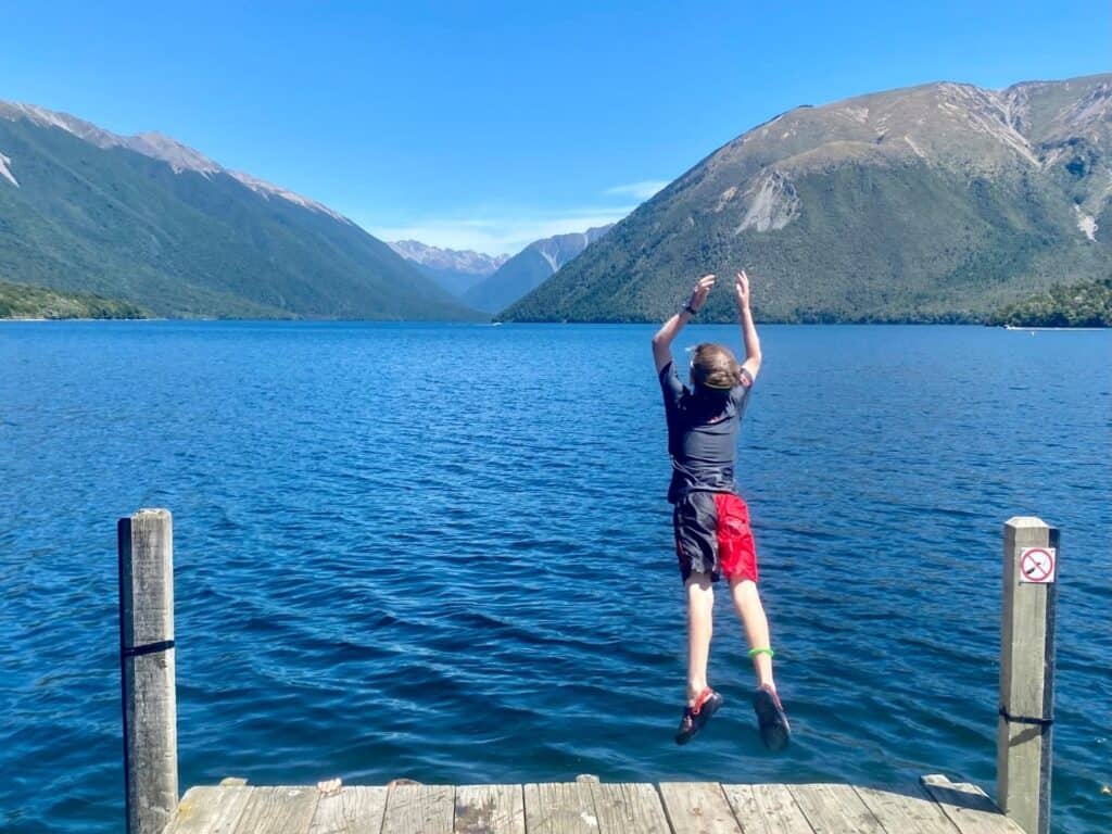 A boy jumping off a dock into the water