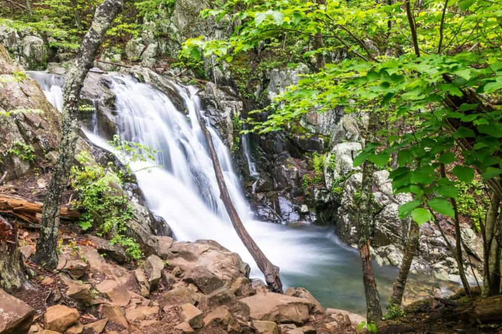 A short waterfall surrounded by rocks and greenery