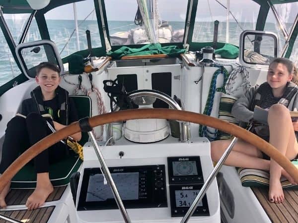 Trent and Katreina, the sailing family's kids, sit on deck of the boat.