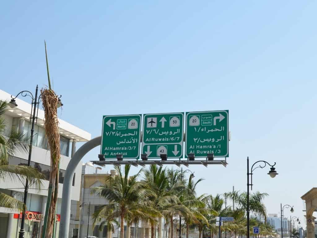 Green and white road signs in English and Arabic