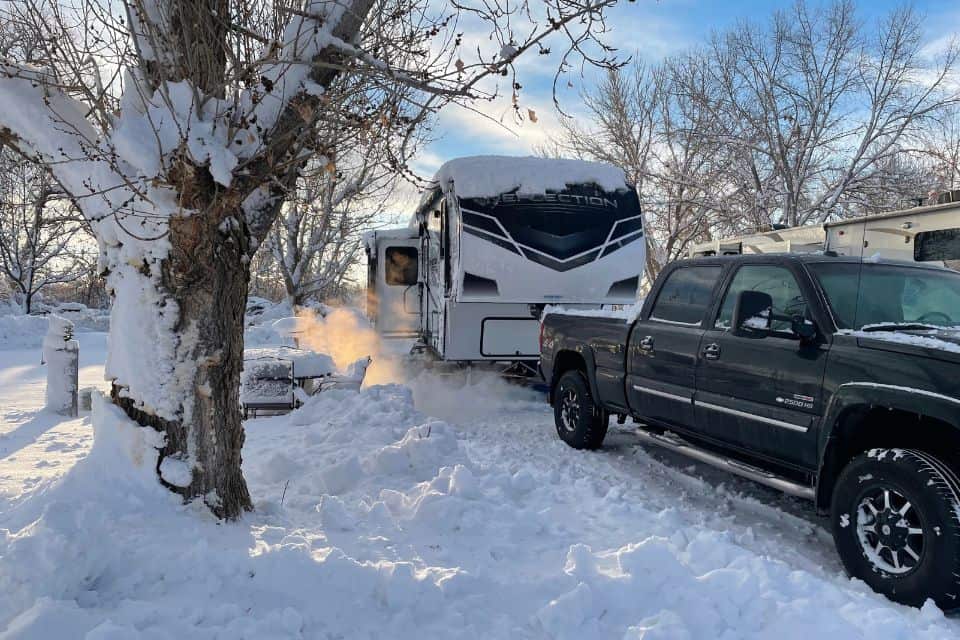 A truck parked in front of a snow-covered RV