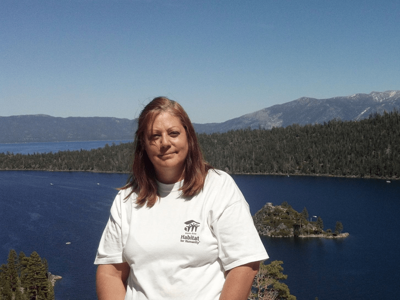 A woman in a white t-shirt sitting in front of a lake