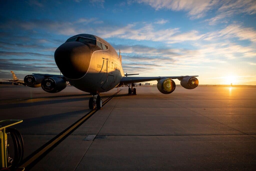 A military aircraft sitting on the runway at sunrise
