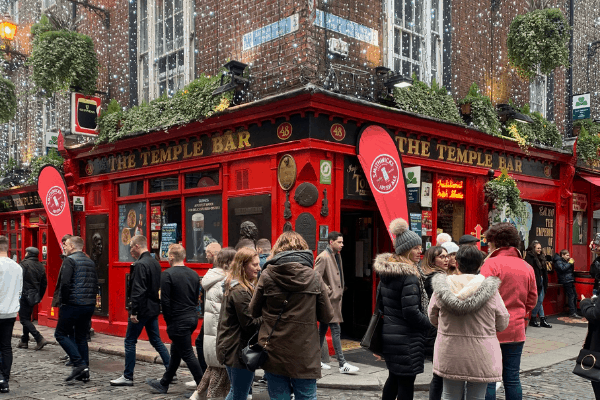 A red pub called The Temple Bar with people standing outside